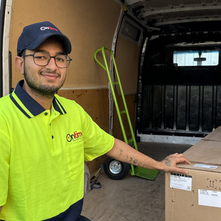 A trustworthy delivery driver looking confidently at the camera, wearing a clean yellow-green uniform.
