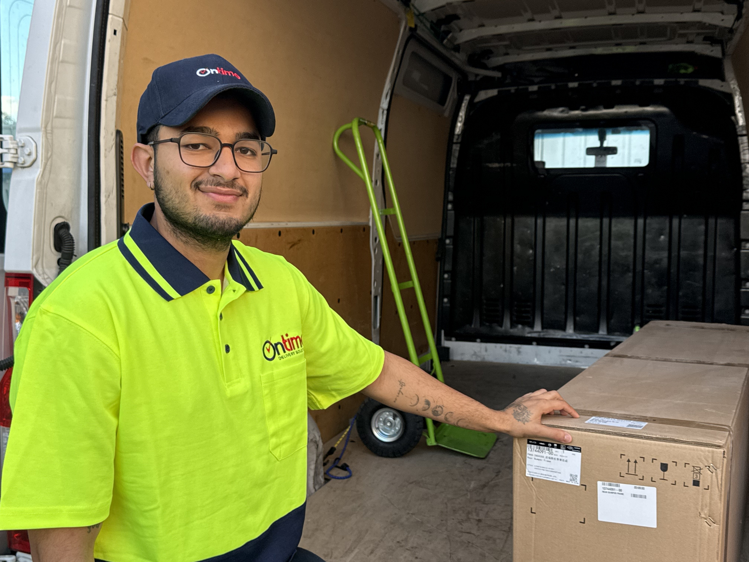 A trustworthy delivery driver looking confidently at the camera, wearing a clean yellow-green uniform.