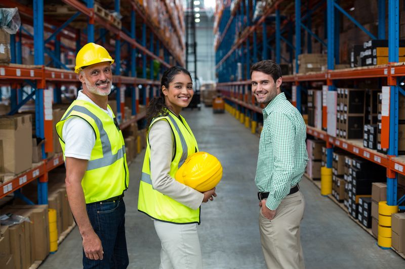 Warehouse management team collaborating in a modern logistics facility focused on safety and efficient supply chain operations.