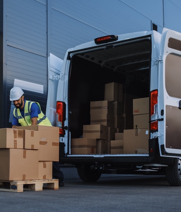 Outside of Logistics Distributions Warehouse With Inventory Manager Using Tablet Computer, talking to Worker Loading Delivery Truck with Cardboard Boxes. Online Orders, Purchases, E-Commerce Goods