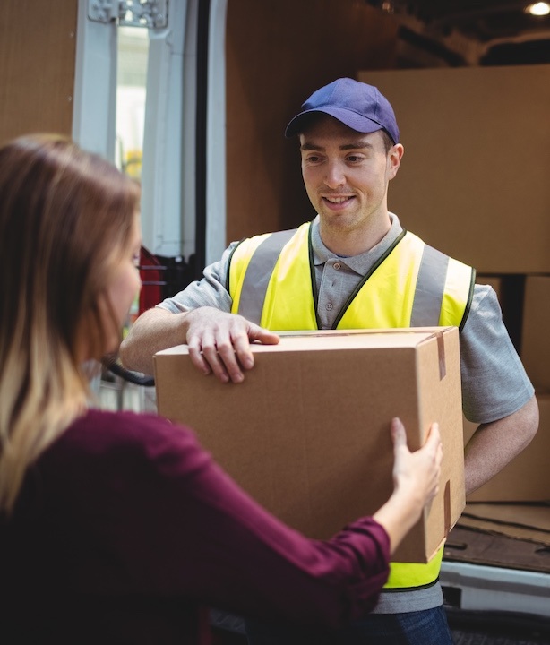 Delivery driver handing parcel to customer outside van