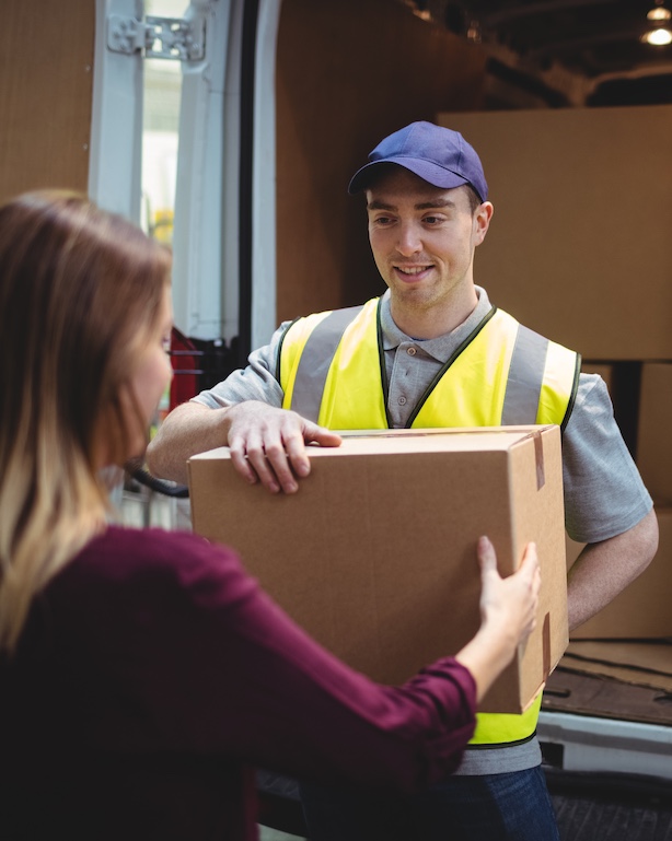 Delivery driver handing parcel to customer outside van